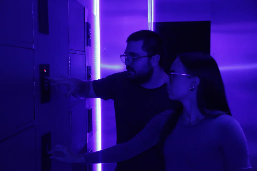 Deux personnes dans une pièce éclairée en violet.