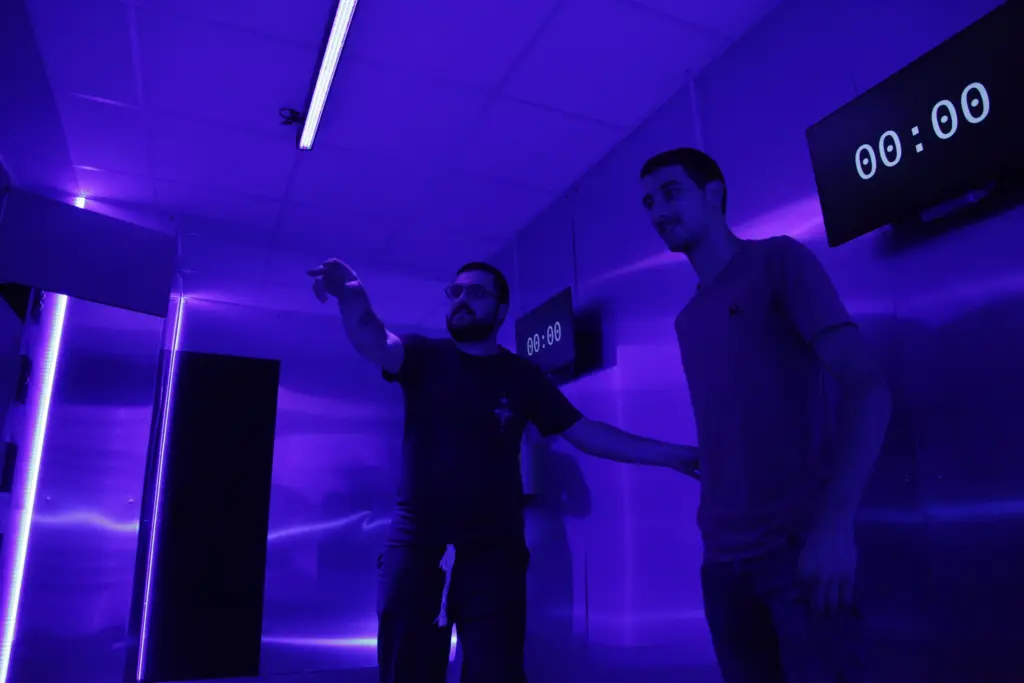 Deux hommes dans une salle éclairée en bleu.