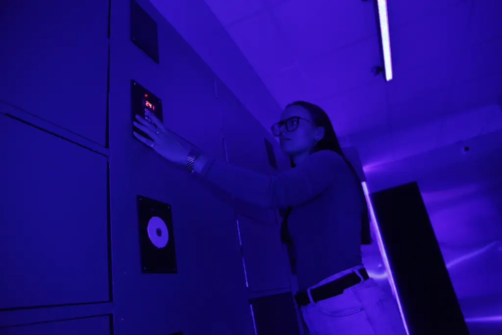 Personne réglant un panneau de contrôle sous lumière violette.