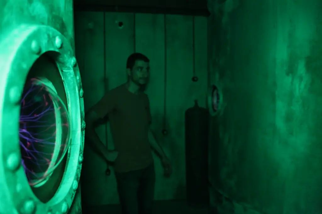 Homme dans une salle métallique avec lumière verte.