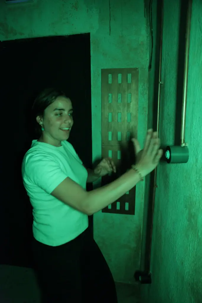 Personne appuyant sur bouton lumineux dans couloir sombre.