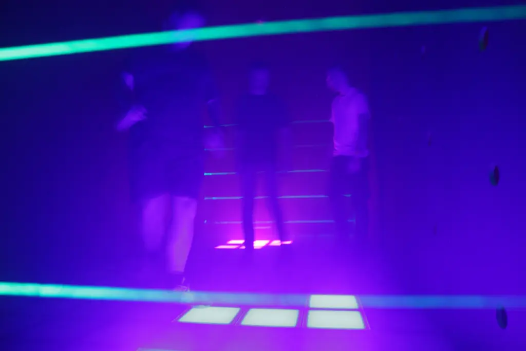 Personnes en salle laser, lumière violette.