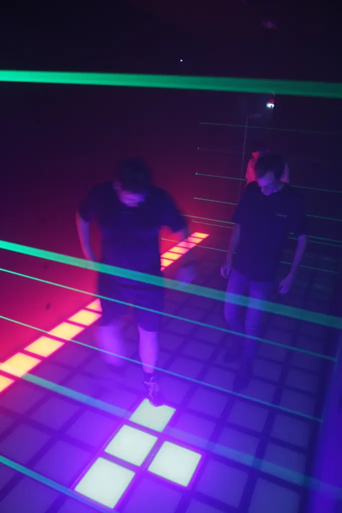 Personnes marchant dans un tunnel laser coloré.