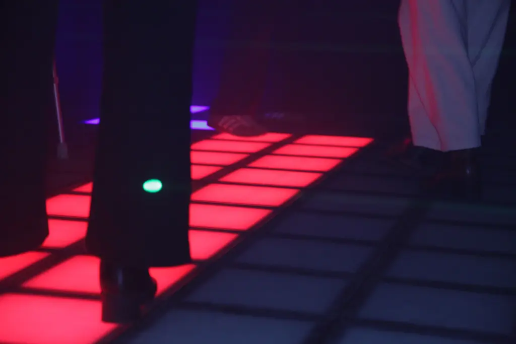 Personnes dansant sur piste lumineuse en soirée