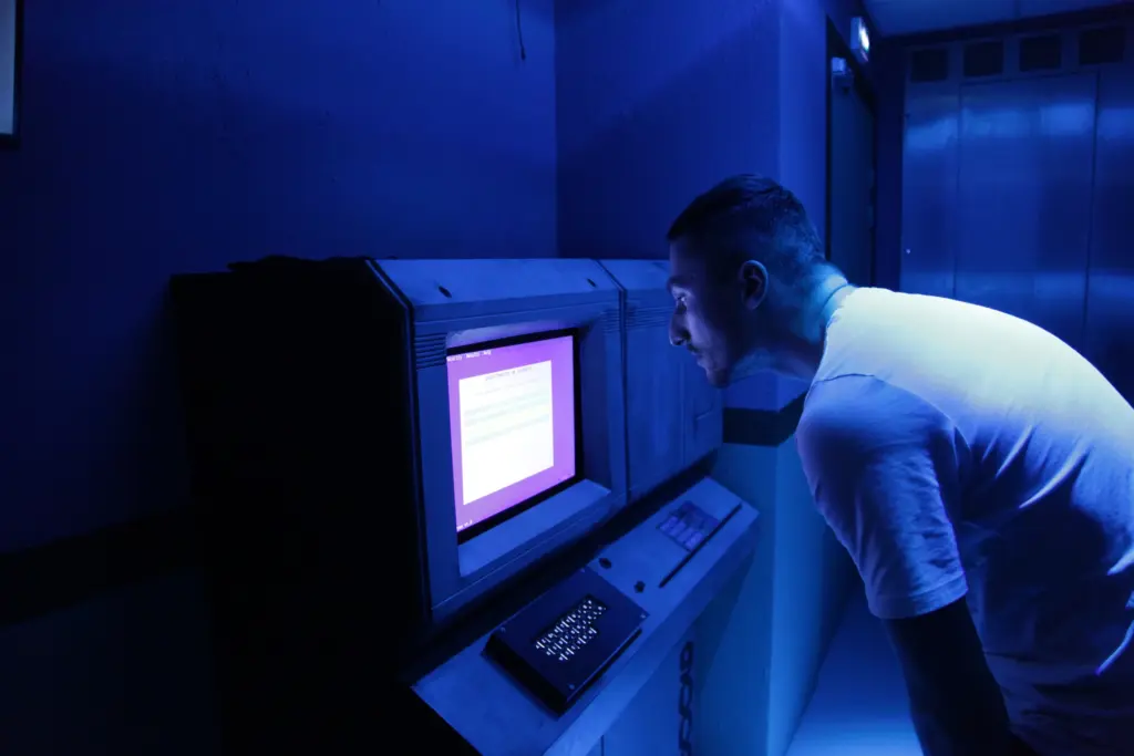 Homme observant un vieil écran d'ordinateur bleu.