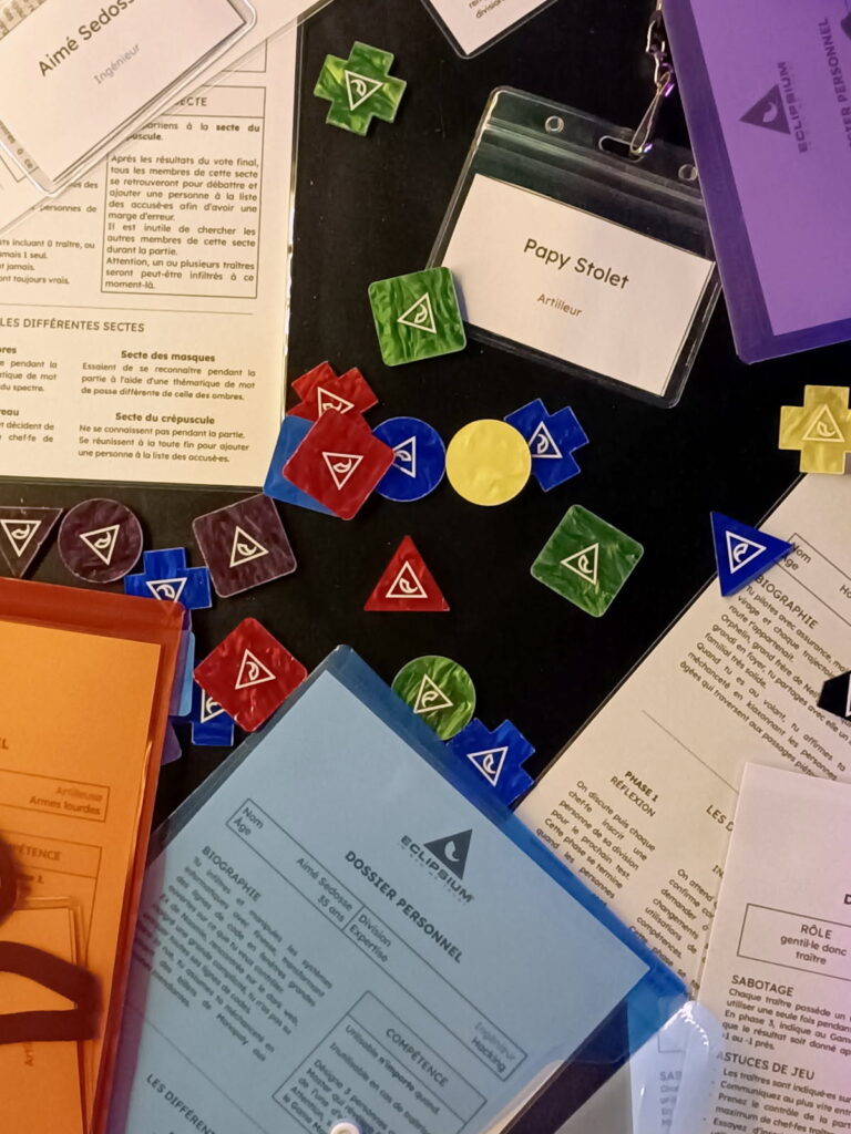 Documents et jetons de jeu sur table noire.