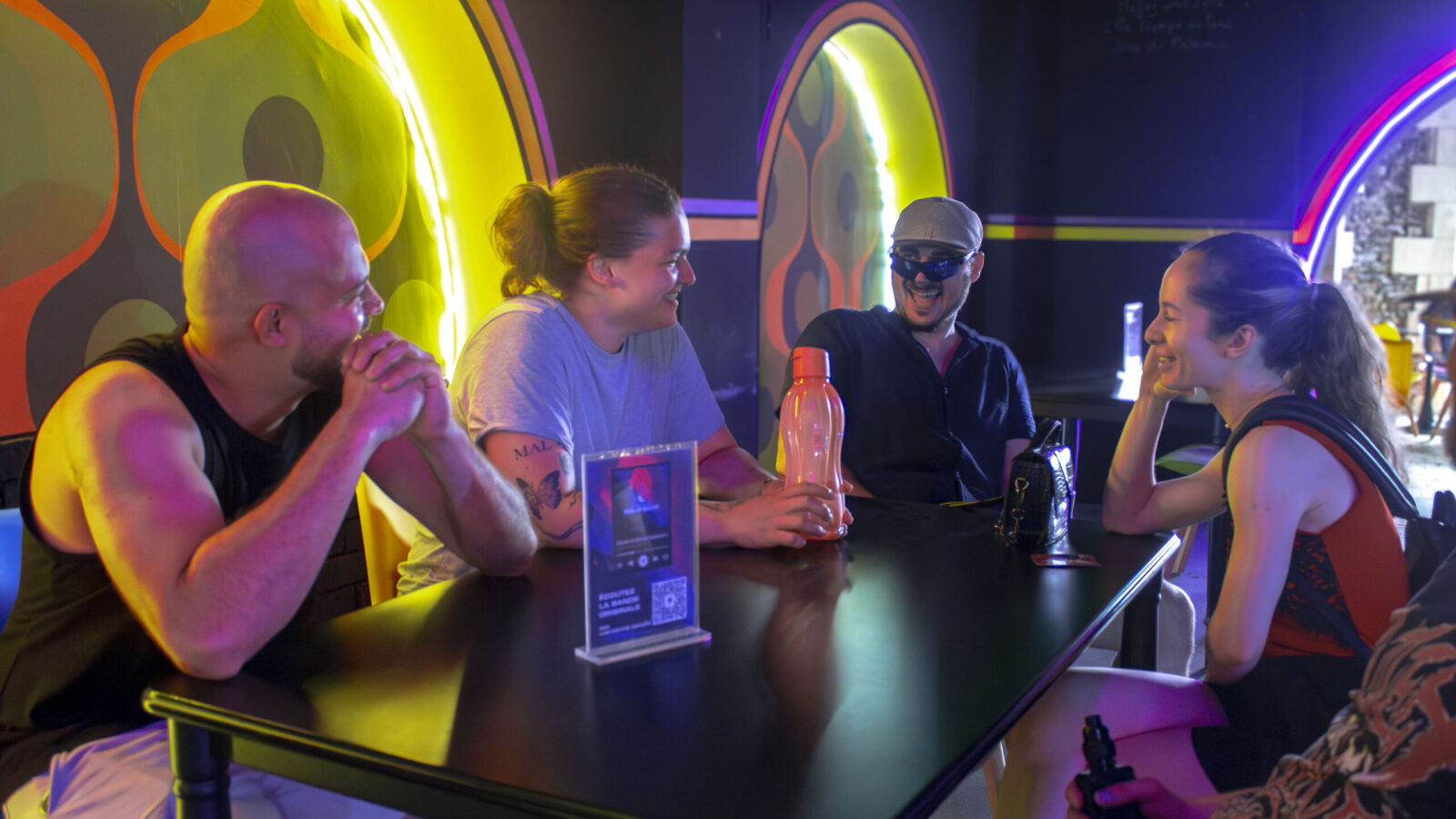 Quatre amis discutent autour d’une table lumineuse